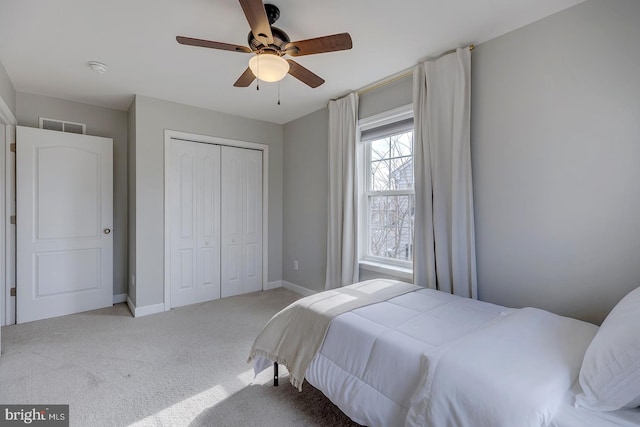 bedroom with a closet, visible vents, a ceiling fan, light carpet, and baseboards