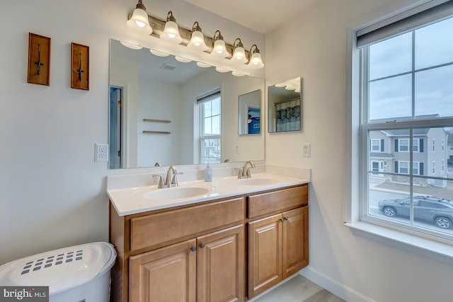 full bath with visible vents, a sink, baseboards, and double vanity