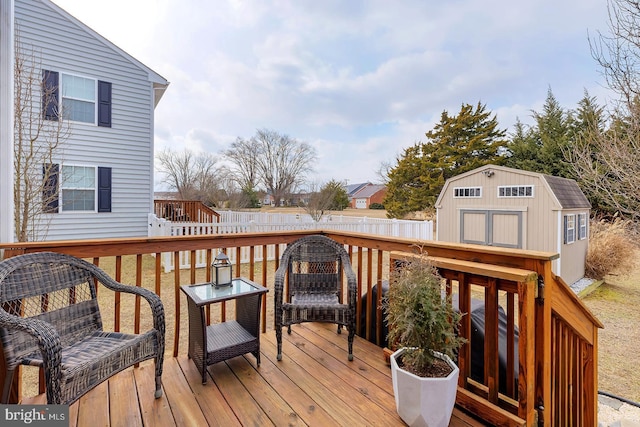 wooden terrace featuring an outbuilding, fence, and a shed