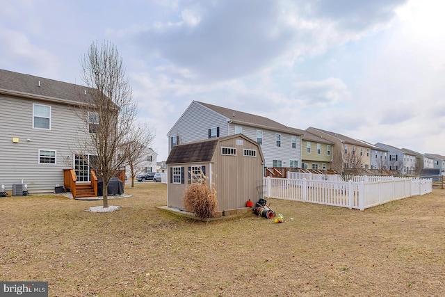 rear view of house with an outdoor structure, fence, a yard, a residential view, and a shed