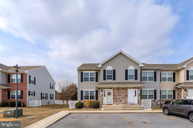 multi unit property featuring stone siding and fence