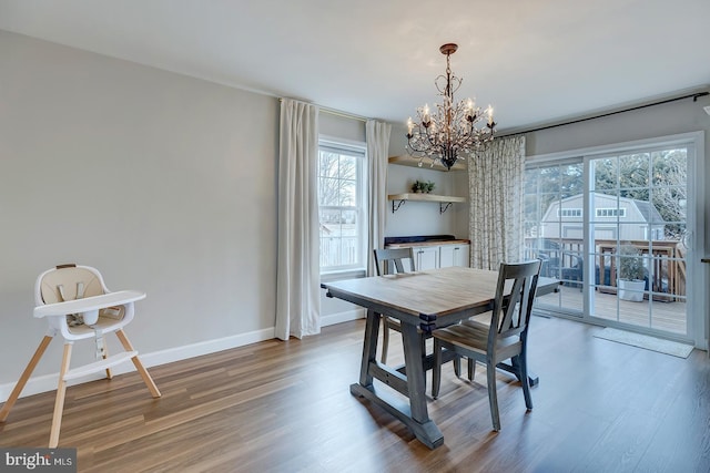 dining area featuring a wealth of natural light, baseboards, wood finished floors, and an inviting chandelier