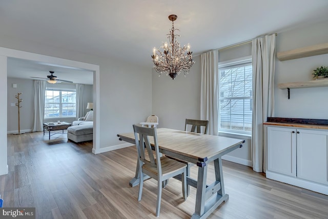 dining area featuring baseboards, light wood finished floors, and ceiling fan with notable chandelier