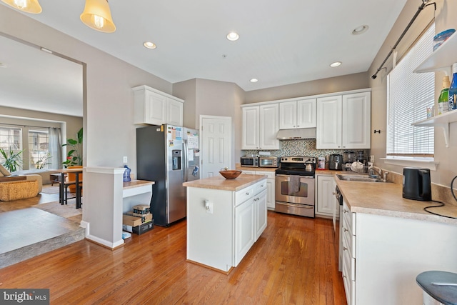 kitchen with under cabinet range hood, a sink, stainless steel appliances, white cabinets, and light countertops