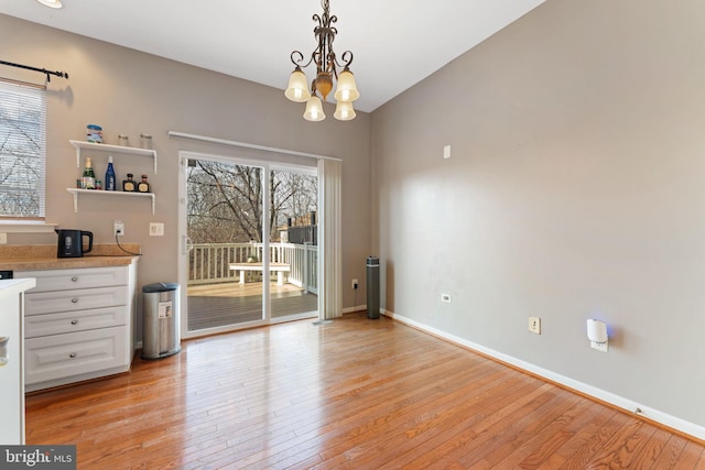 unfurnished dining area featuring plenty of natural light, light wood-style floors, and an inviting chandelier