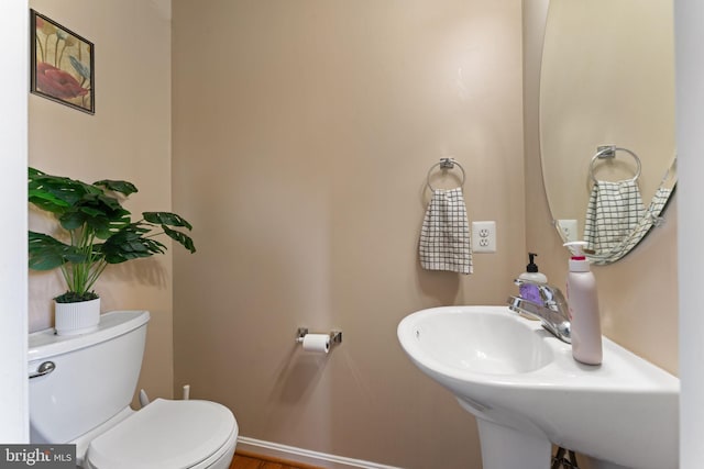 bathroom with toilet, baseboards, and a sink