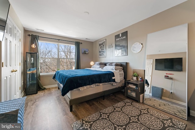 bedroom with visible vents, baseboards, and wood finished floors