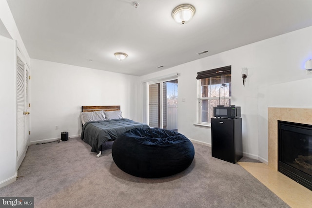 bedroom featuring visible vents, a fireplace with flush hearth, carpet, and baseboards