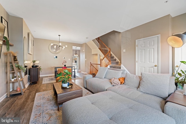 living room featuring baseboards, stairs, an inviting chandelier, and wood finished floors