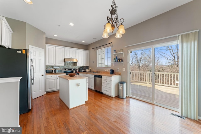 kitchen with visible vents, a kitchen island, stainless steel appliances, under cabinet range hood, and white cabinetry