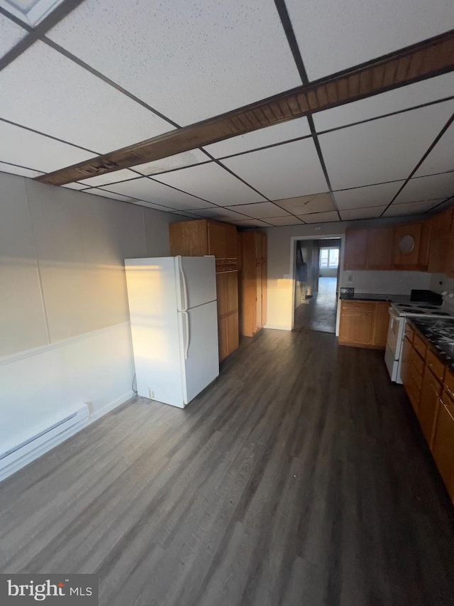 kitchen featuring brown cabinets, dark countertops, a paneled ceiling, dark wood-type flooring, and white appliances