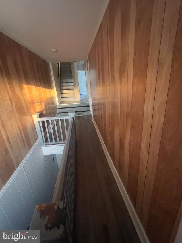 hallway featuring wood walls and an upstairs landing