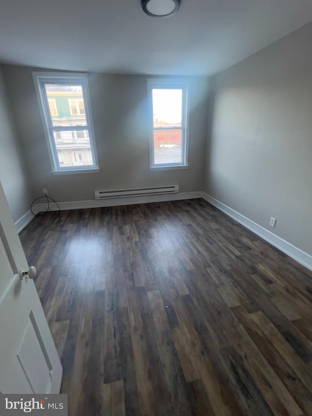 unfurnished room with baseboards, baseboard heating, and dark wood-type flooring