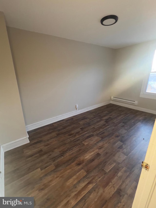 unfurnished room with dark wood-style floors, baseboards, and baseboard heating