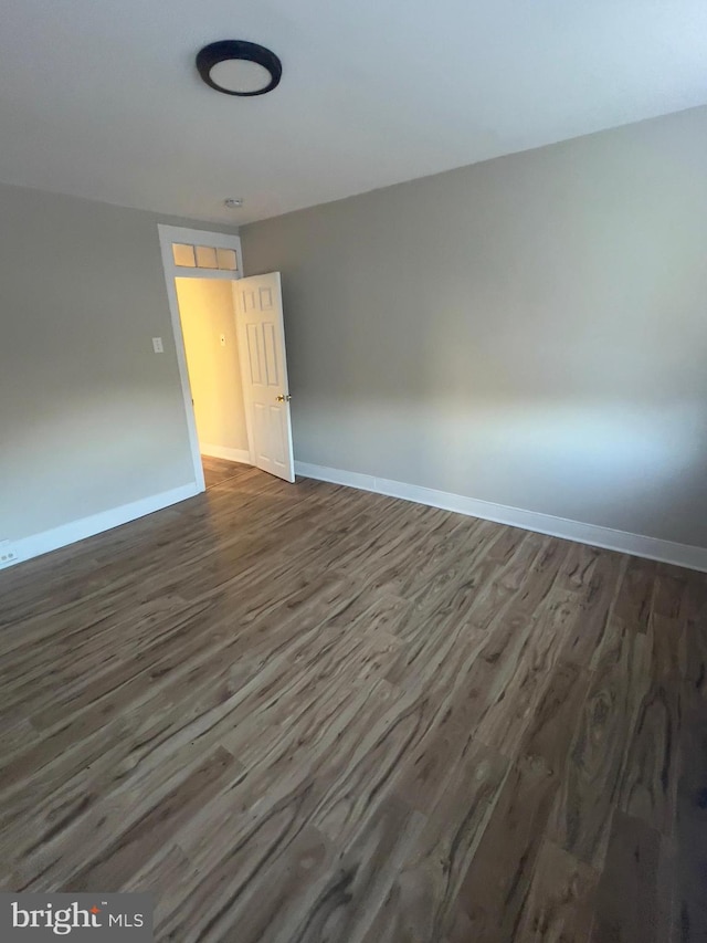 unfurnished room featuring dark wood-style flooring and baseboards