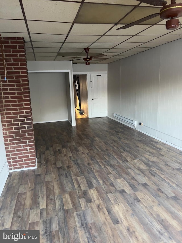 spare room featuring a drop ceiling, a ceiling fan, baseboard heating, and dark wood-style flooring