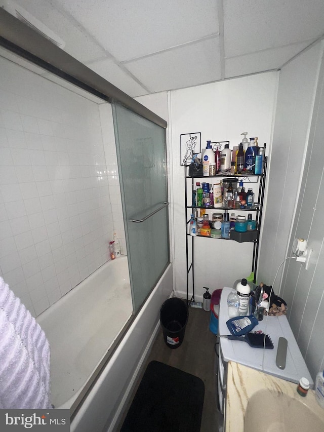 full bathroom with a paneled ceiling and bath / shower combo with glass door