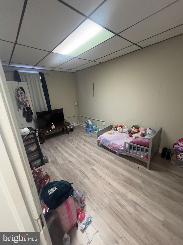 bedroom with a paneled ceiling and wood finished floors