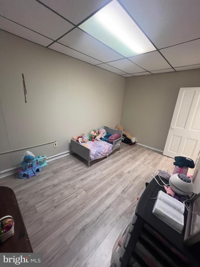 bedroom with a paneled ceiling, baseboards, and wood finished floors