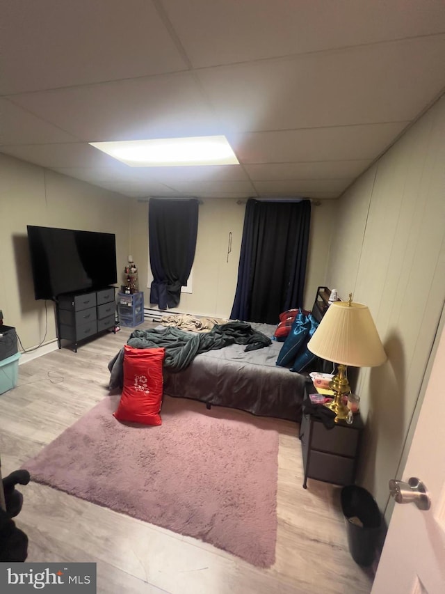 bedroom featuring light wood-type flooring and a drop ceiling