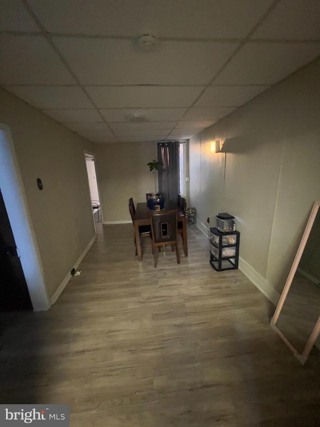 dining area featuring a drop ceiling, wood finished floors, and baseboards