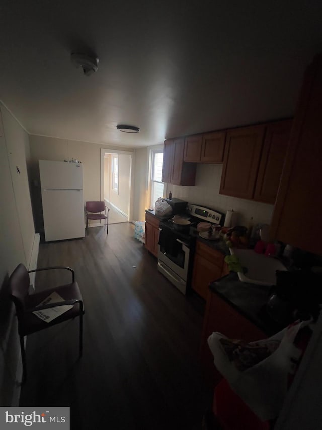 kitchen featuring dark wood-style floors, electric stove, freestanding refrigerator, and brown cabinets