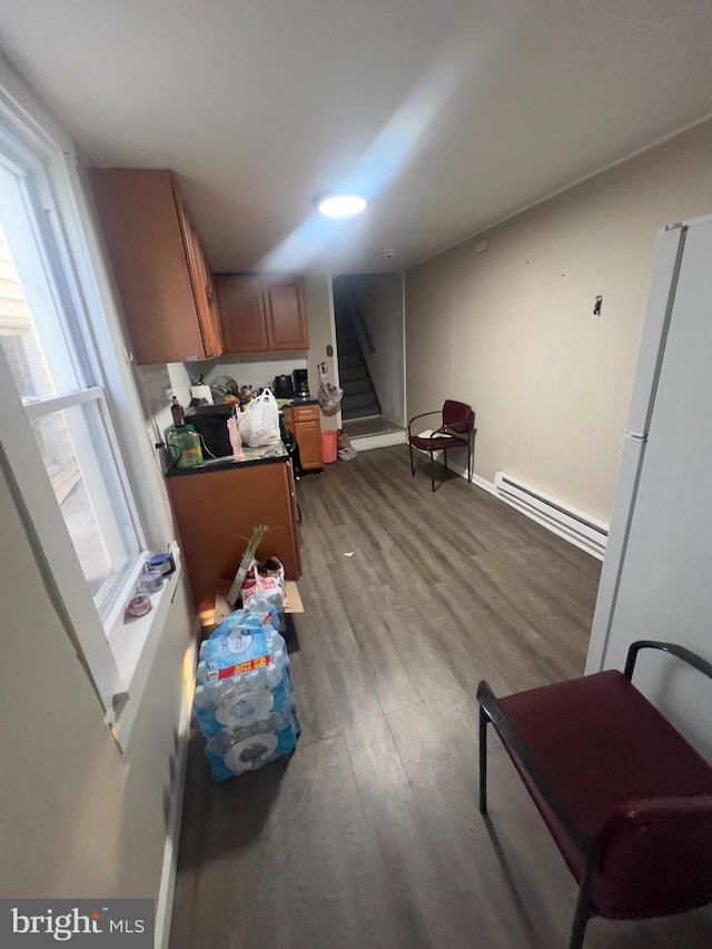 kitchen featuring a healthy amount of sunlight, a baseboard radiator, brown cabinetry, and wood finished floors