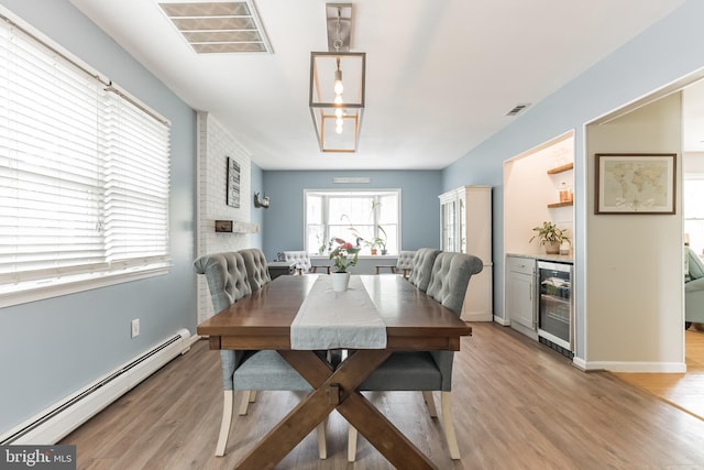 dining area featuring light wood-style floors, a baseboard radiator, beverage cooler, and visible vents