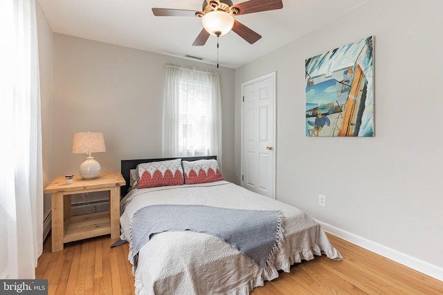 bedroom featuring visible vents, ceiling fan, baseboards, and hardwood / wood-style flooring