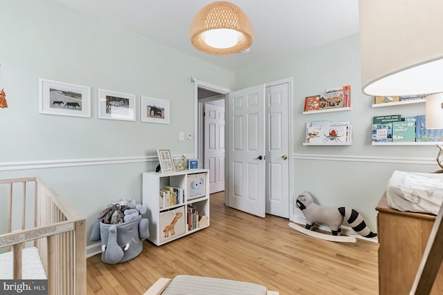 bedroom with a nursery area, a closet, and wood finished floors