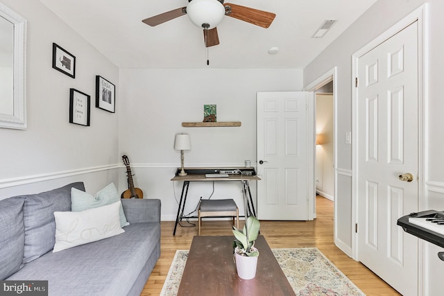 living room featuring baseboards, visible vents, ceiling fan, and light wood finished floors