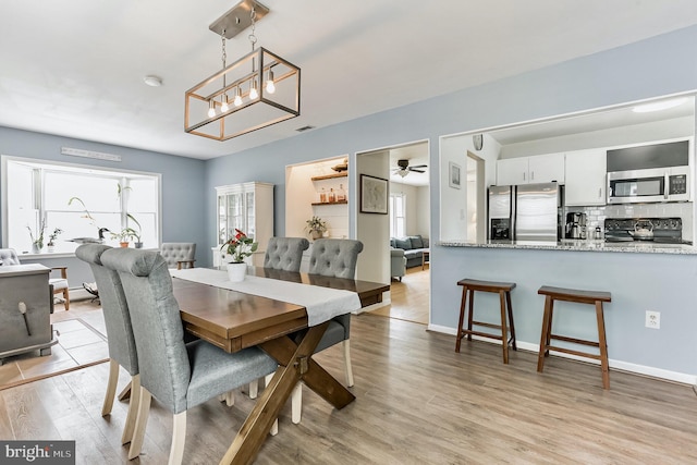 dining room featuring a ceiling fan, a wealth of natural light, visible vents, and light wood finished floors