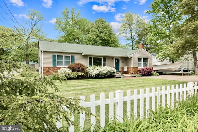 view of front of home with a fenced front yard, brick siding, roof with shingles, a chimney, and a front lawn