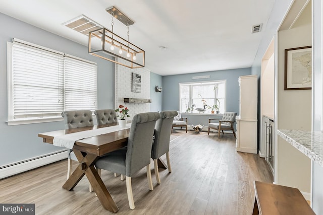 dining space featuring visible vents, a fireplace, and light wood-style flooring