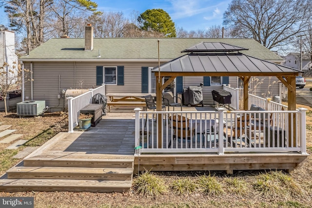 back of property with a shingled roof, a chimney, a gazebo, a wooden deck, and central air condition unit