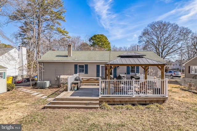 back of property with cooling unit, fence, a gazebo, a lawn, and roof with shingles