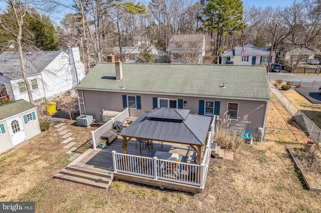 rear view of property featuring a yard, a chimney, a shingled roof, a gazebo, and a wooden deck