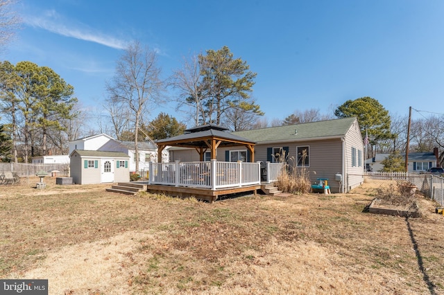 rear view of property with a gazebo, fence, a wooden deck, and an outbuilding