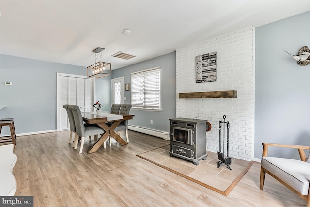 dining space with light wood finished floors, a baseboard radiator, visible vents, and baseboards