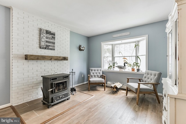 sitting room featuring a wood stove, baseboards, and wood finished floors