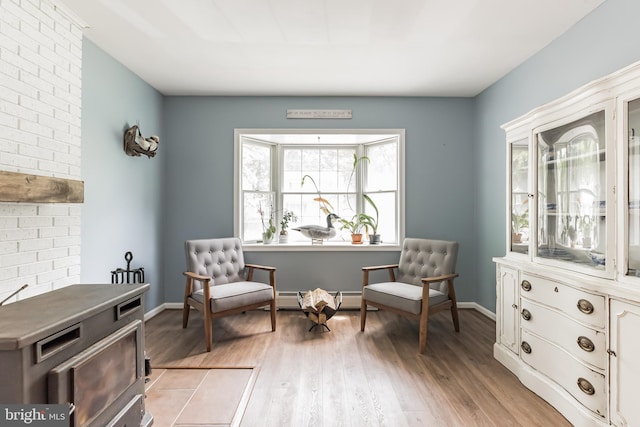 sitting room featuring baseboard heating, light wood-type flooring, and baseboards