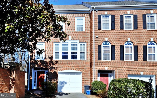 view of property featuring a garage, brick siding, and driveway