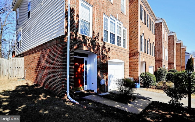 view of building exterior featuring driveway, an attached garage, and fence