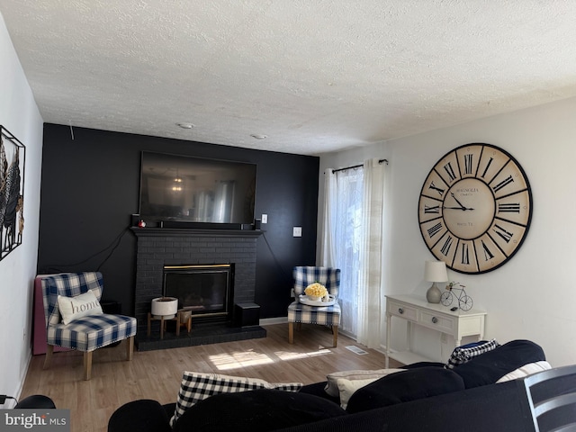 living room with a textured ceiling, a fireplace, wood finished floors, and visible vents