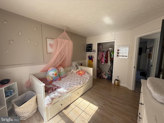 bedroom featuring a textured ceiling, a closet, and wood finished floors