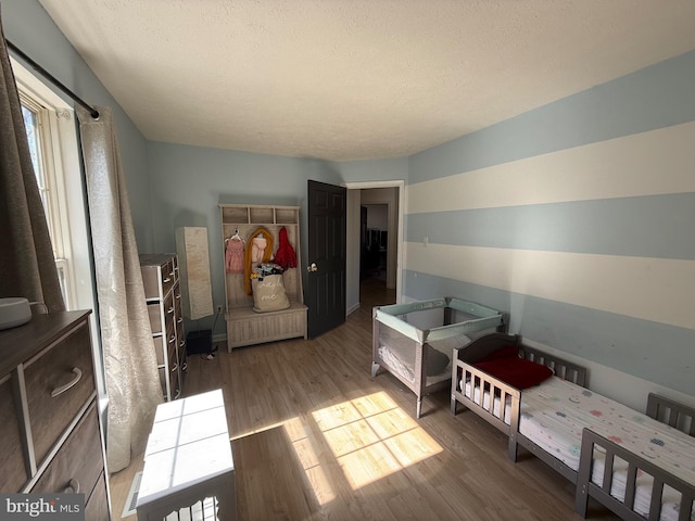 bedroom featuring multiple windows, a textured ceiling, and wood finished floors