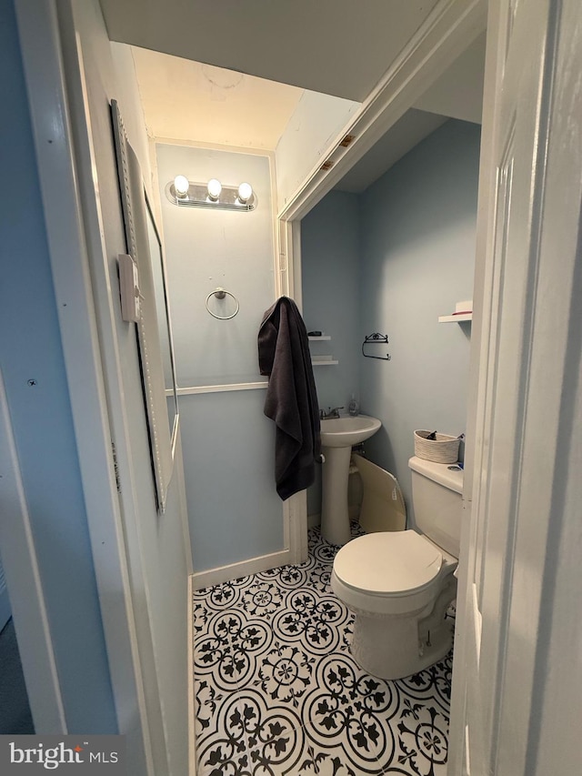 half bathroom featuring tile patterned flooring, a sink, and toilet