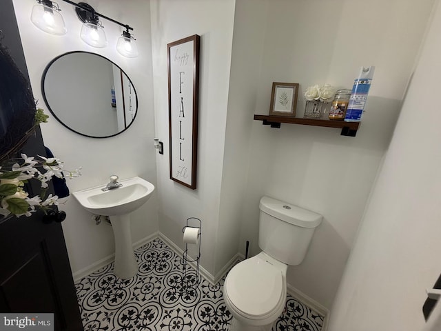 half bath featuring tile patterned flooring, baseboards, and toilet