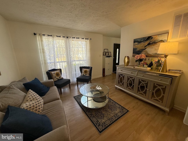 living area with a textured ceiling, baseboards, and wood finished floors