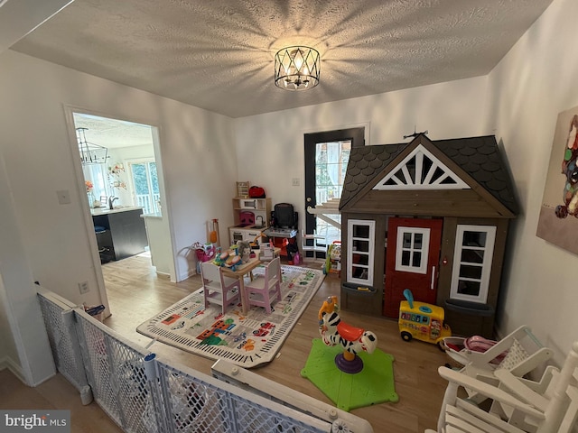 playroom with plenty of natural light, a notable chandelier, and a textured ceiling